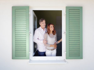 Paar am Fenster mit grünem Fensterladen