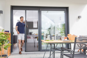 Mann geht durch eine Terrassentüre mit Plissee